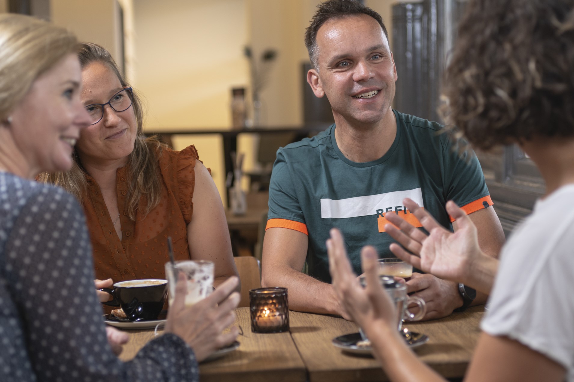 Drie vrouwen en man in gesprek met koffie