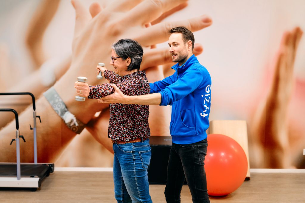 Fysiotherapeut laat vrouw oefenen met gewichten