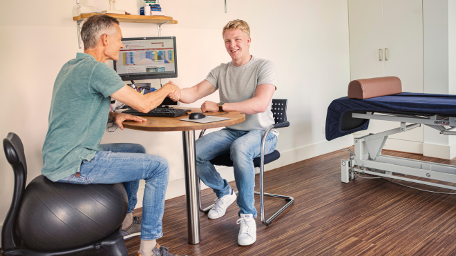 Mannen aan bureau schudden elkaar de hand