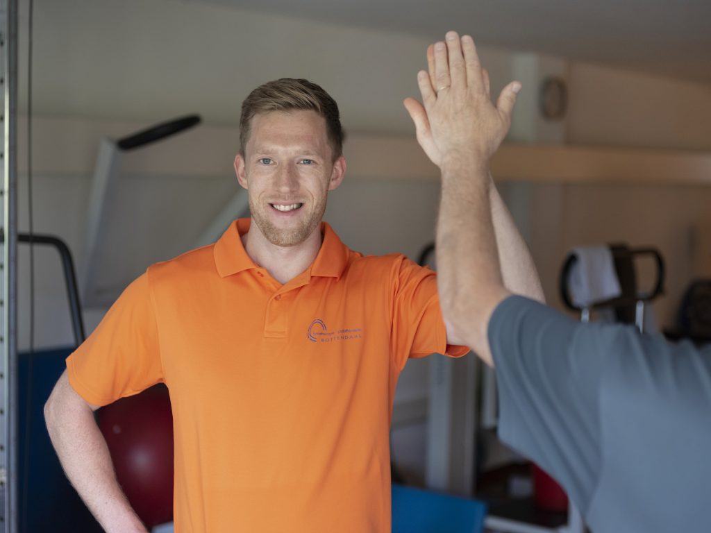 man met oranje shirt geeft highfive