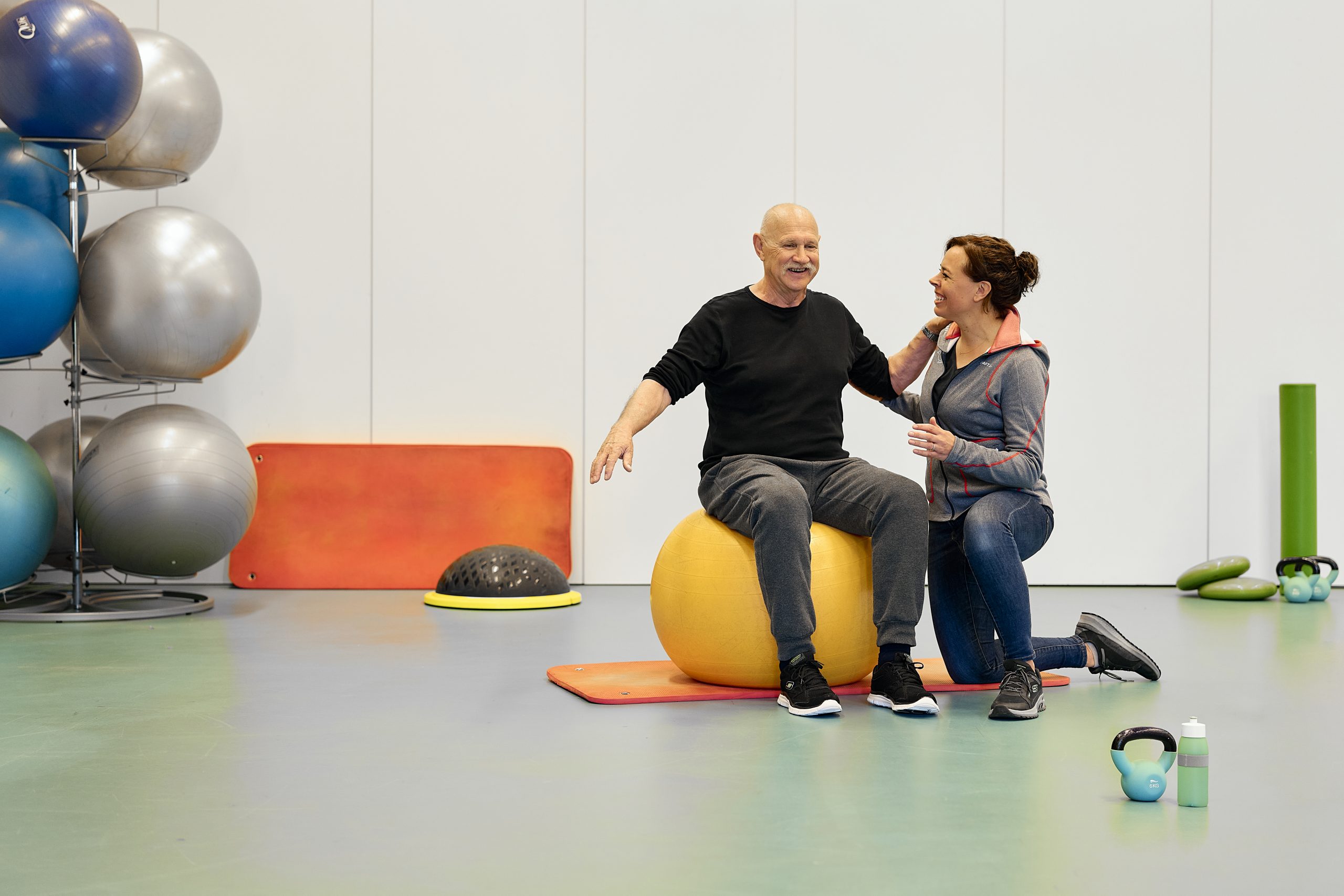 Fysiotherapeut Maria Roelofsen helpt Hans met een oefening op een bal.