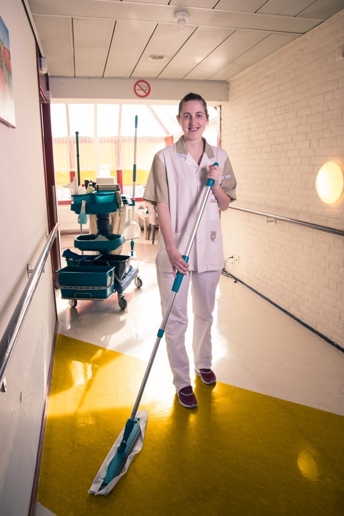 Schoonmaakster aan het werk vloeren aan het dweilen