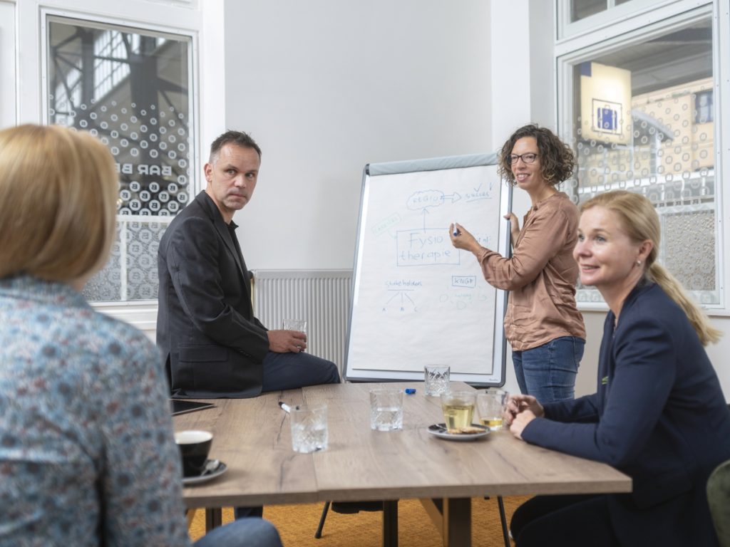 Vier mensen voor whiteboard die iets opschrijven