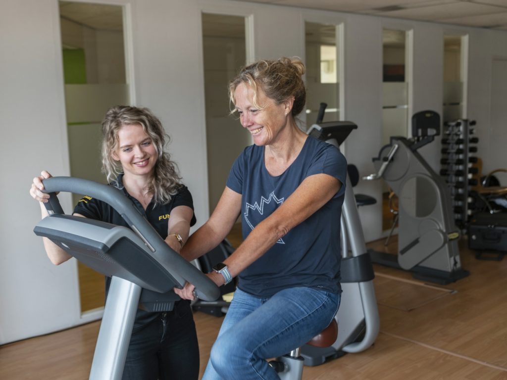 Fysiotherapeut en patiënt op hometrainer